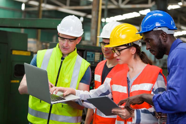 a group of people in high-vis vests looking at a computer.